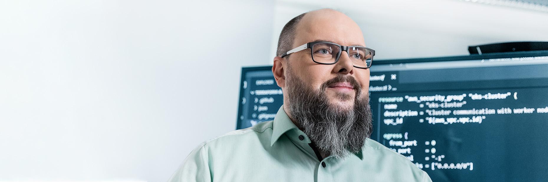 Sven steht vor einem großen Bildschirm, auf dem Programmcode angezeigt wird